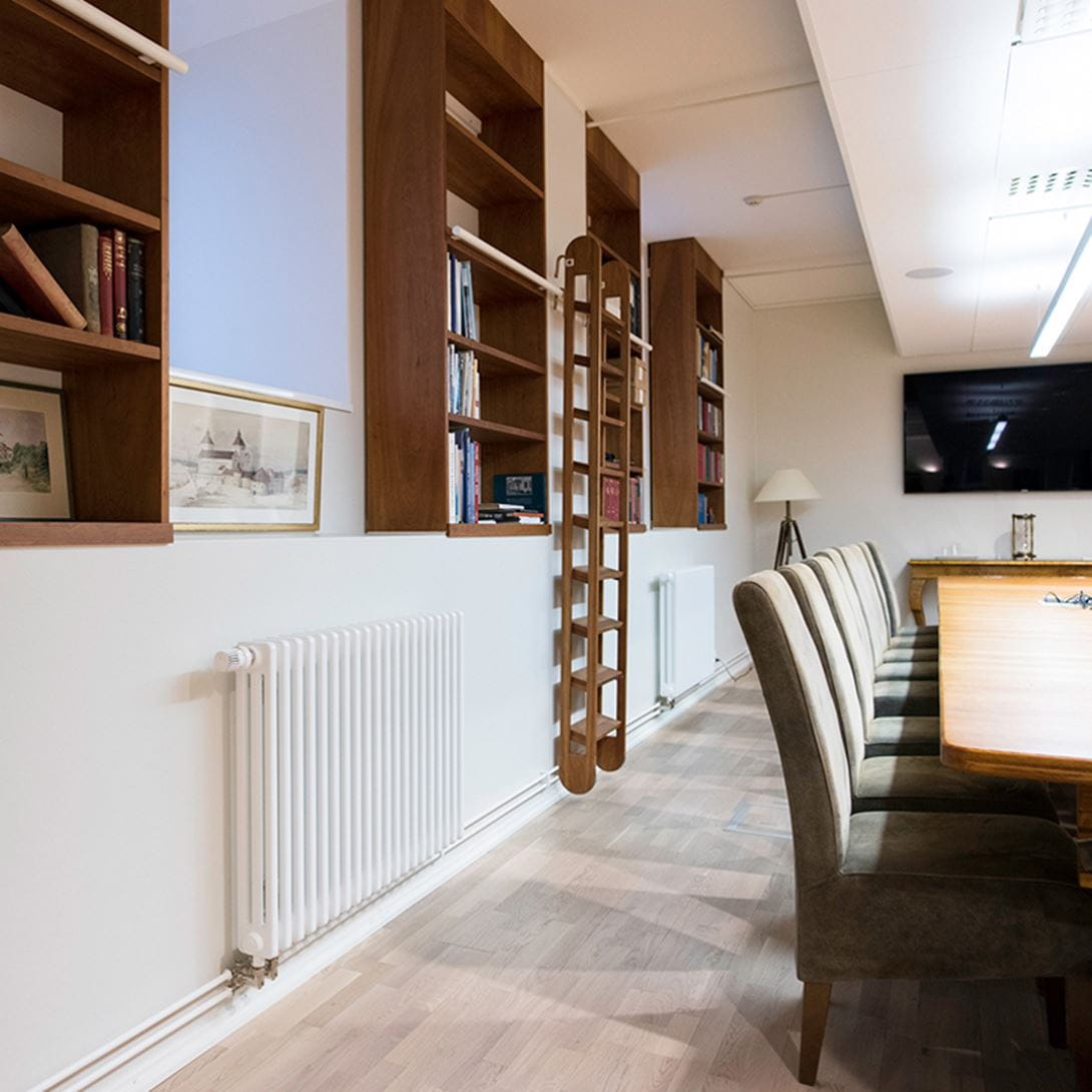 Purmo Delta column radiators in an office space. Visible piping in office radiators.