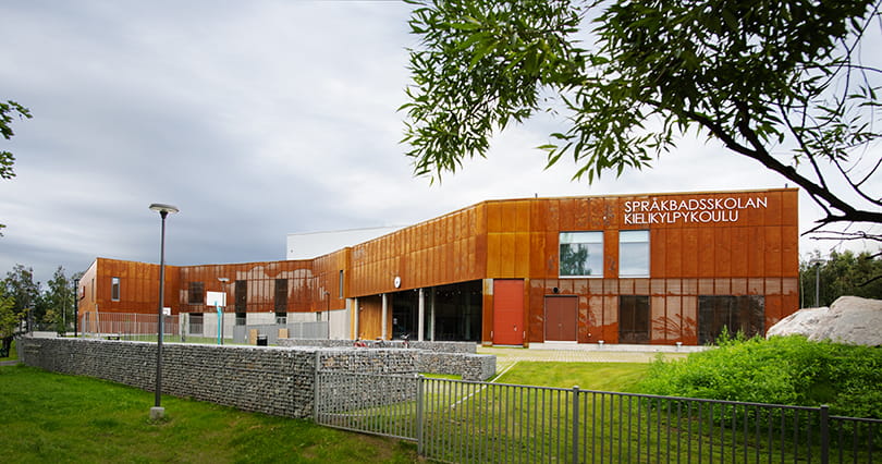 Språkbadsskolan har en modern fasad i rost.